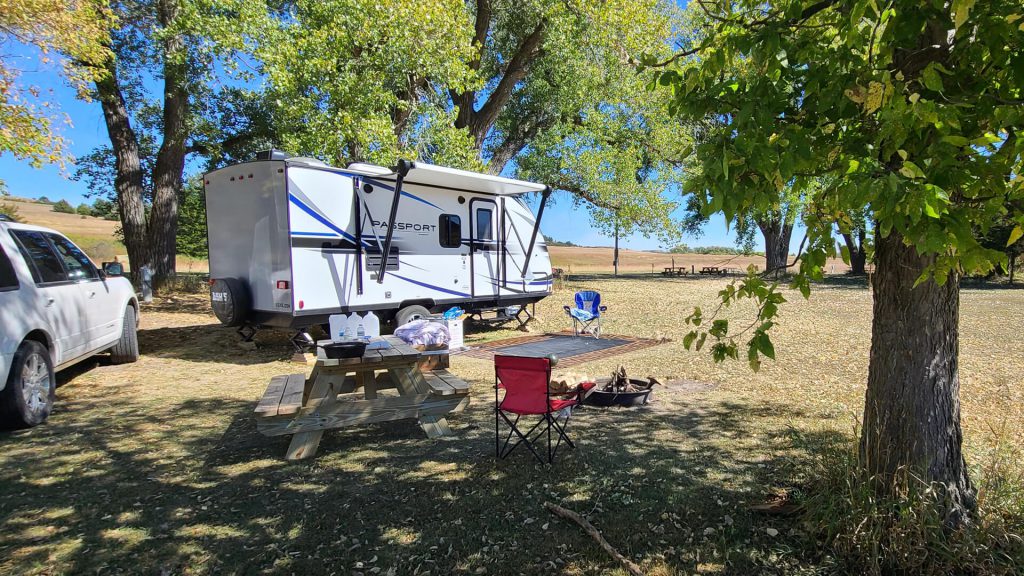 Camper set up near picnic table and fire pit
